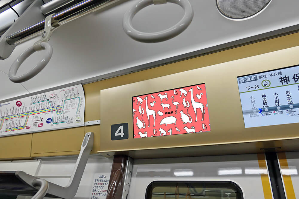 京王電鉄の各車両ドア上部に運行情報用のディスプレイと並列で設置されている、ヨコ型のデジタルサイネージ