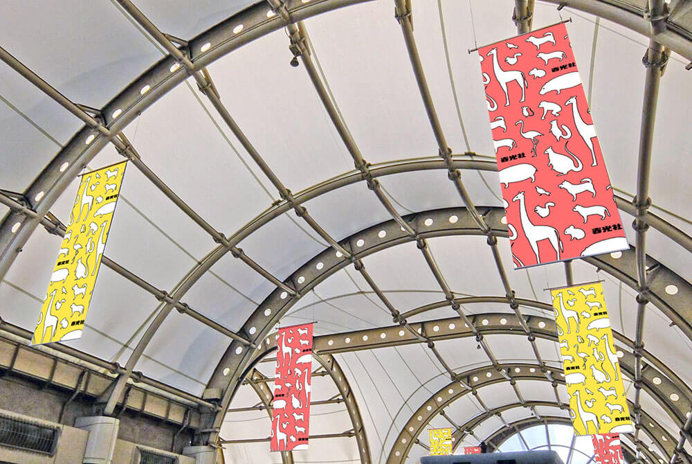 りんかい線国際展示場駅改札内コンコース天井部から吊るされている、乗降客の導線上にあるタテ長大型サイズで訴求率の高い目立つ媒体